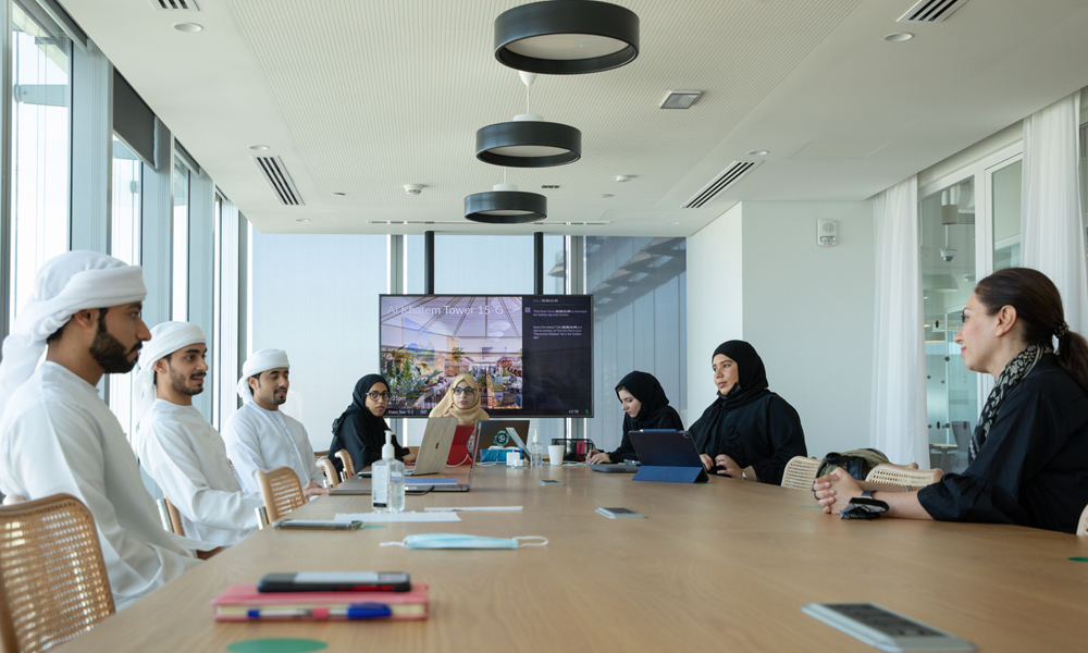 A group of Emirati students engaged in a discussion with a presentation on a screen - MIT Innovation Leadership Boot camp