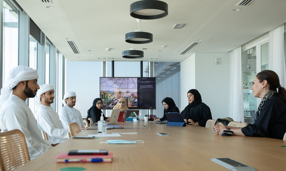 MIT-Leadership-bootcamp A group of Emirati students engaged in a discussion with a presentation on a screen - MIT Innovation Leadership Boot camp