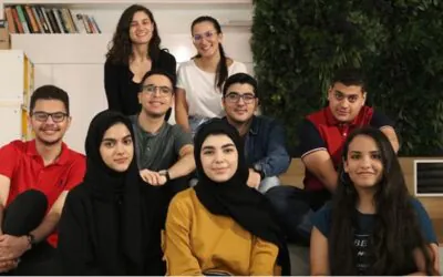 Group of students posing on wooden steps indoors, dressed in casual attire - AGF