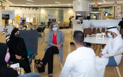 Officials of the Abdulla Al Ghurair Foundation seated in a cafe-style workspace, engaged in discussion.