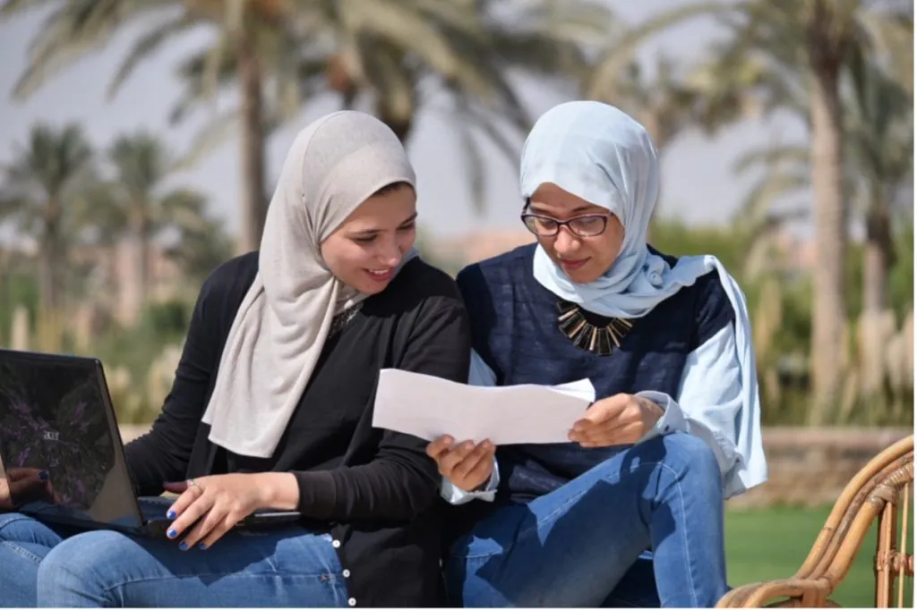 Two women Scholars from AGF are sitting outdoors and engaged in a discussion.