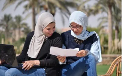 Two women Scholars from AGF are sitting outdoors and engaged in a discussion.