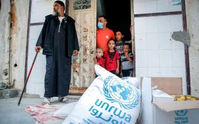A family stands at the entrance of a building during a relief distribution by AGF in Gaza