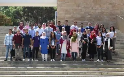 Group photo of AGF scholars standing on a wide outdoor staircase in front of a stone wall