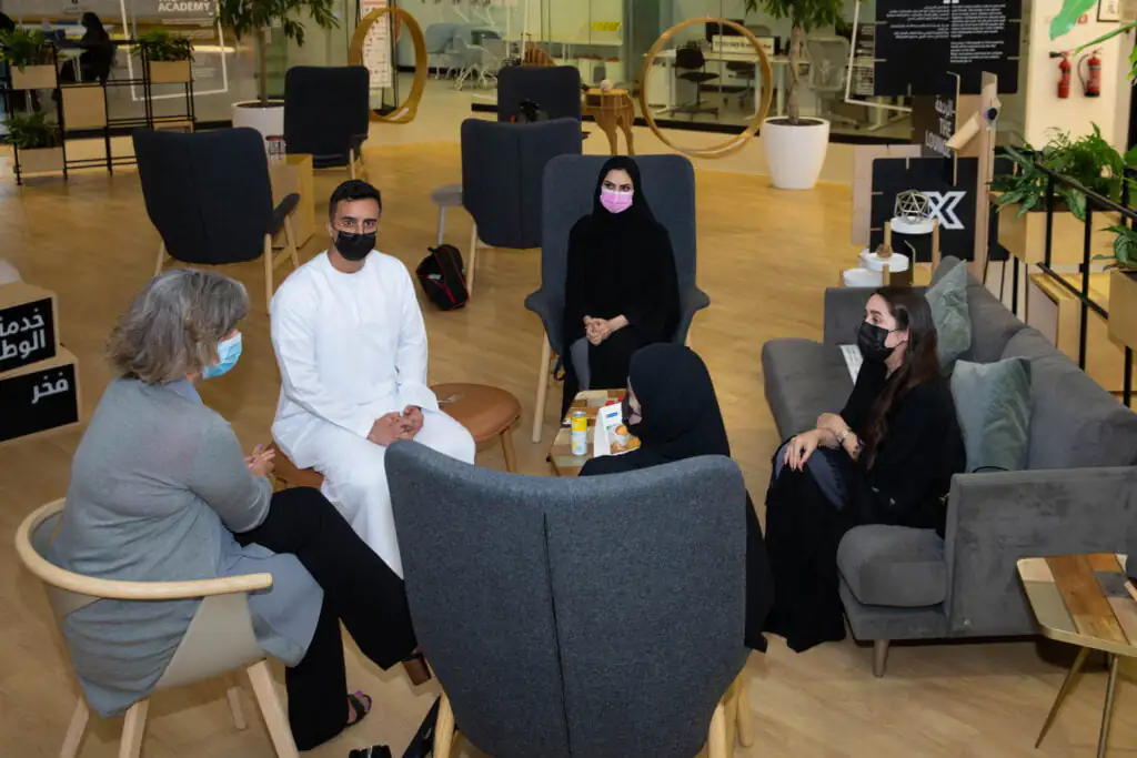 Six individuals, including officials from the AGF, are seated in a modern workspace, engaged in conversation.