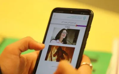 A person holds a smartphone displaying the AGF website interface.