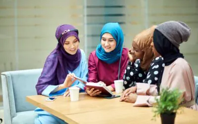 Four Arab women students sit around a table, engaged in a collaborative discussion.