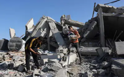 Two people in Gaza amid rubble, salvaging books from a collapsed concrete structure.