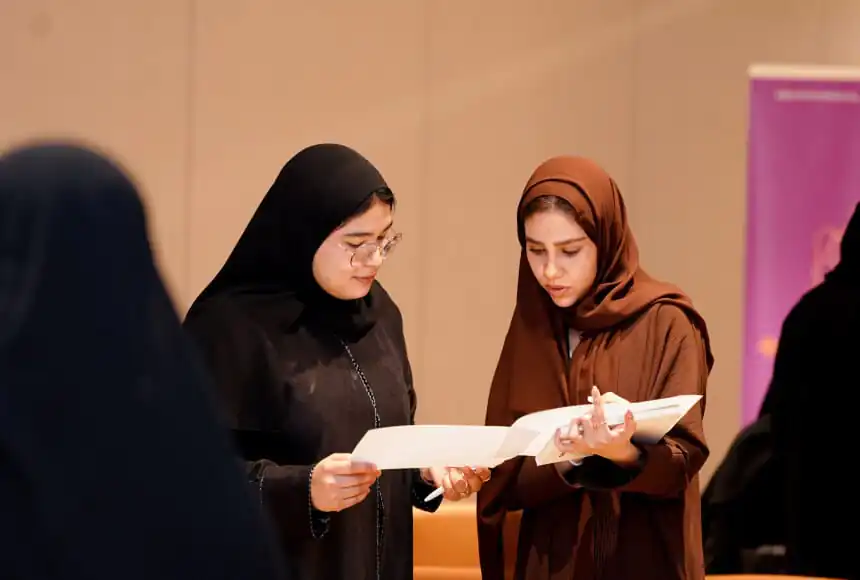 Two Arab women students, reviewing documents and discussing together